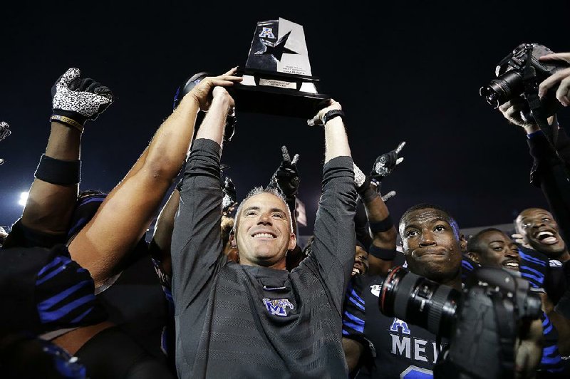 Memphis Coach Mike Norvell (center) lifts the American Athletic Conference West Division championship trophy Friday after the No. 18 Tigers defeated No. 19 Cincinnati 34-24 at the Liberty Bowl in Memphis. The two teams will play again next week in Memphis for the conference championship. 