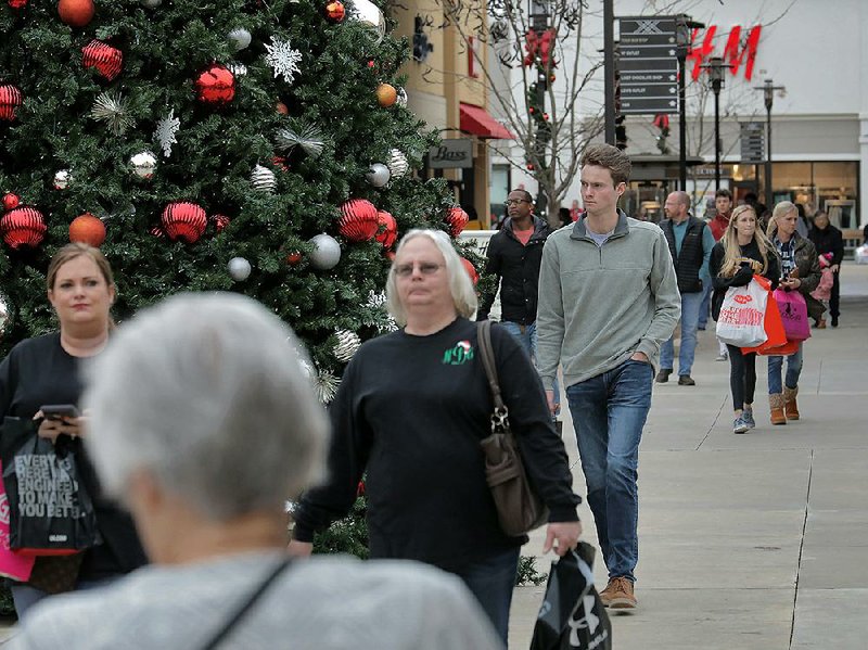 Customers pass a Christmas tree Friday at the Outlets of Little Rock. A National Retail Federation survey said U.S. retailers will ring up between $727.9 billion and $730.7 billion in Christmas sales in November and December. More photos are available at arkansasonline.com/1130sales 