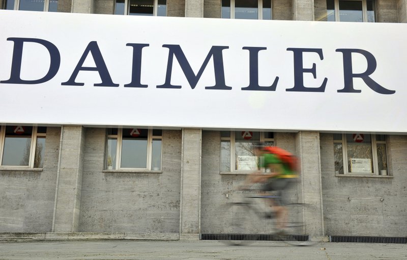 FILE - In this April 8, 2009 file photo, a cyclist passes a logo of German car company Daimler in Berlin. German automaker Daimler said Friday, Nov. 29, 2019 that it plans to cut at least 10,000 jobs worldwide by the end of 2022.  (AP Photo/Gero Breloer, file)