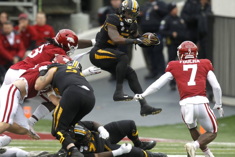 Missouri running back Larry Rountree III (34) hurdles a teammate as he is chased by Arkansas defensive back Joe Foucha (7) during the first quarter of the Razorbacks’ 24-14 loss to Missouri on Friday at War Memorial Stadium in Little Rock. - Photo by Thomas Metthe of the Arkansas Democrat-Gazette