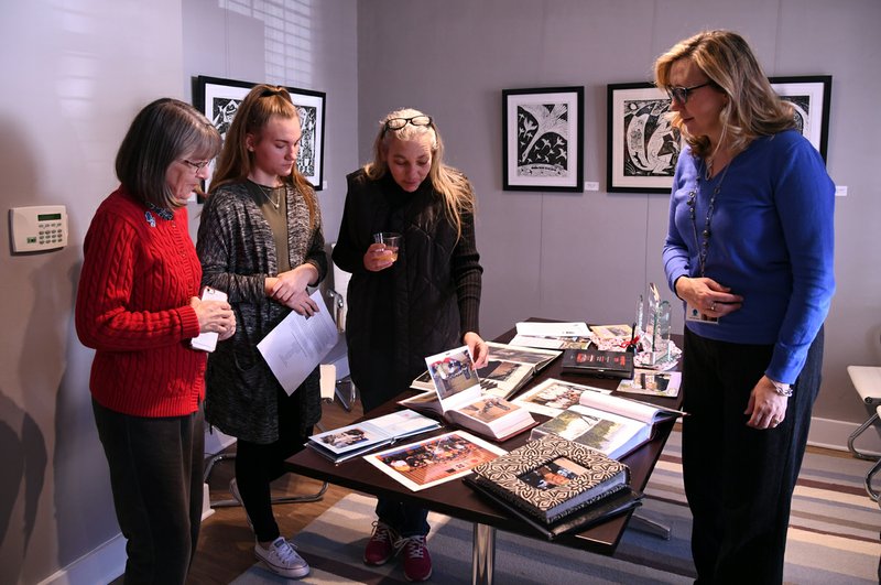 From left, Kristina Coleman, Tammy Brown, Bayley Brown and Mary Zunick look over photographs of past visits to Hanamaki, Japan, that local students and adults have made through the Sister City Program in January 2018. - File photo by Grace Brown of The Sentinel-Record