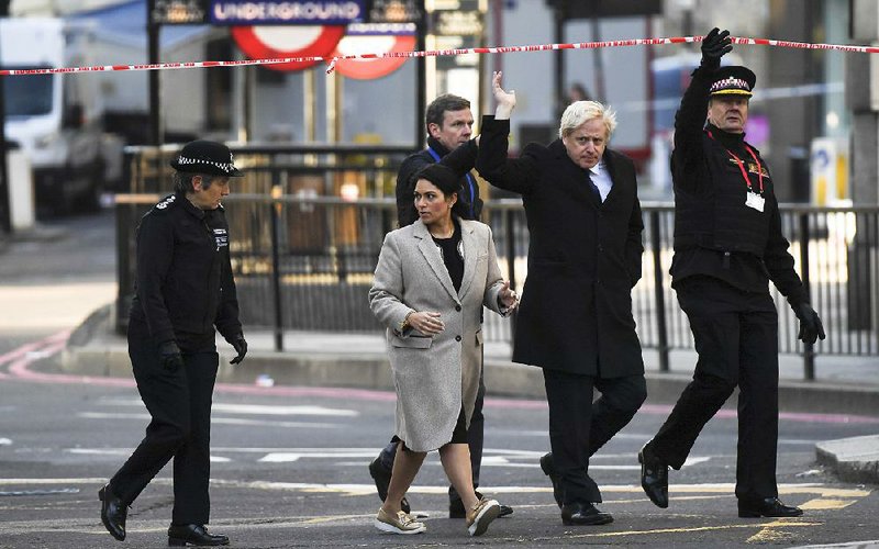 British Prime Minister Boris Johnson (second from right) and Homeland Secretary Priti Patel visit the scene Saturday near London Bridge where a man fatally stabbed two people on Friday. More photos at arkansasonline.com/121london/ 