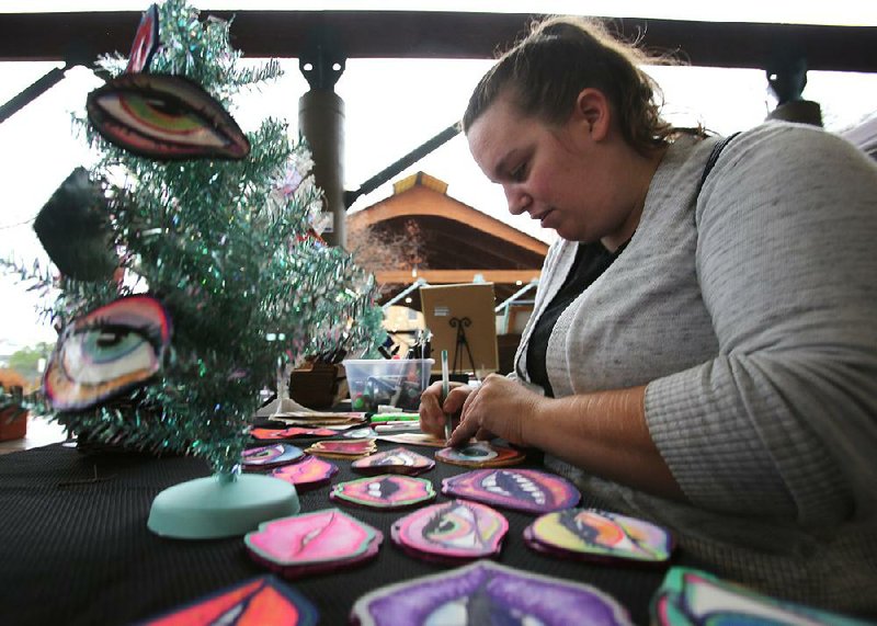 Jennie Sanderson works on her eyes artwork Saturday in her booth during the third annual Small Business Saturday event in the Little Rock River Market.