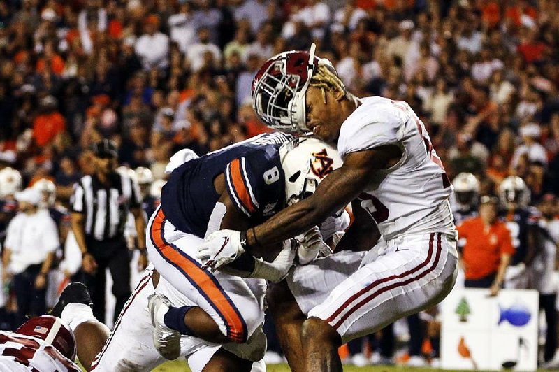 Alabama defensive back Xavier McKinney (right) loses his helmet as Auburn running back Shaun Shivers runs through him en route to the go-ahead touchdown in the fourth quarter of the Tigers’ victory over the Crimson Tide on Saturday. 