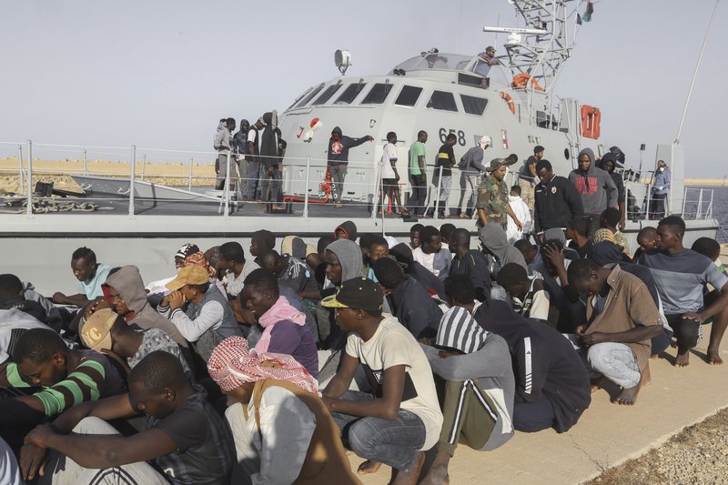  In this Oct. 1, 2019 file photo, rescued migrants are seated next to a coast guard boat in the city of Khoms, around 120 kilometers (75 miles) east of Tripoli, Libya.  (AP Photo/Hazem Ahmed, File)
