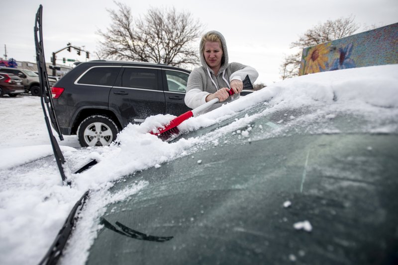 Brittany Culp cleans snow off her windshield Saturday in Greeley, Colo. The city canceled its Greeley Lights the Night parade Saturday because of the weather. More photos at arkansasonline.com/121wintry/ 