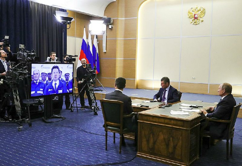 Russian President Vladimir Putin (right) and two of his agency ministers hold a video conference with Chinese President Xi Jinping on Monday during the inauguration of the “Power of Siberia” gas pipeline. 