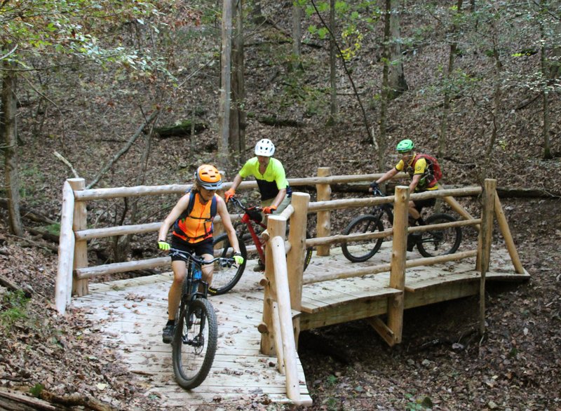 Michele Jackson, Tommy Farris, and Randy Jackson cross a picturesque bridge in this 2019 file photo at Hobbs State Park-Conservation Area Monument trail. (Special to the Democrat-Gazette/BOB ROBINSON)