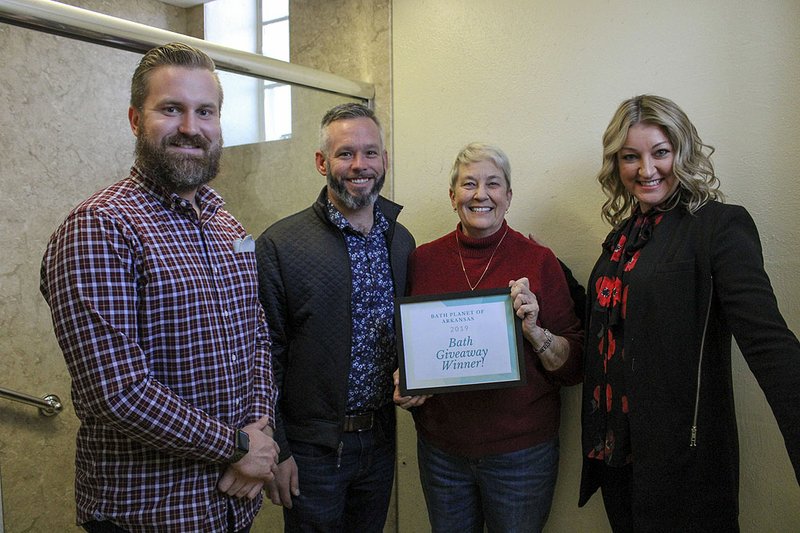 Elliot Thomas, left, Chris Cusick, and Nicole Cusick, right, of Bath Planet of Arkansas, join Sally Carter with St Luke's Episcopal Church inside a bathroom stall that was recently converted into a shower for the local homeless population to use on Monday. Bath Planet of Arkansas donated and installed the shower and The Giving Circle donated the funds to cover modifications to the infrastructure. - Photo by Grace Brown of The Sentinel-Record story.lead_photo.caption