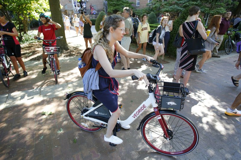 In this 2018 file photo, Misty Orpin, with Economic Development at the University of Arkansas, goes for a ride after using the VeoRide app following the ceremony officially starting the VeoRide bike sharing program on the campus in Fayetteville.