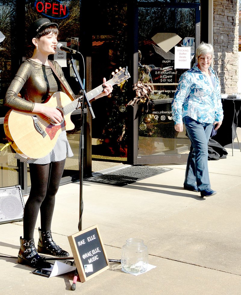Keith Bryant/The Weekly Vista Centerton resident Rae Elle plays her guitar and sings outside Linden's Jewelry during last weekend's Small Business Saturday.