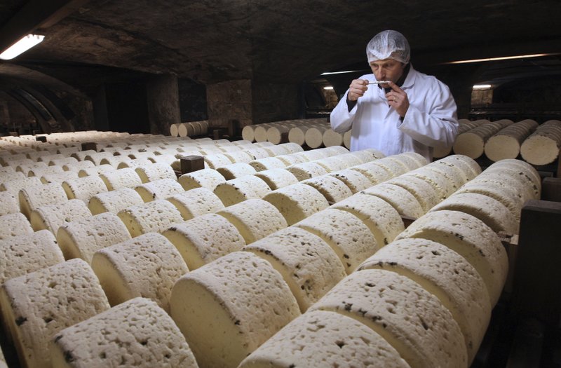 In this Jan. 21, 2009, file photo, Bernard Roques, a refiner of Societe company, smells a Roquefort cheese as they mature in a cellar in Roquefort, southwestern France. The Trump administration is proposing tariffs on up to $2.4 billion worth of French imports, from Roquefort cheese to handbags, retaliation for France's tax on American tech giants like Google, Amazon and Facebook. 
