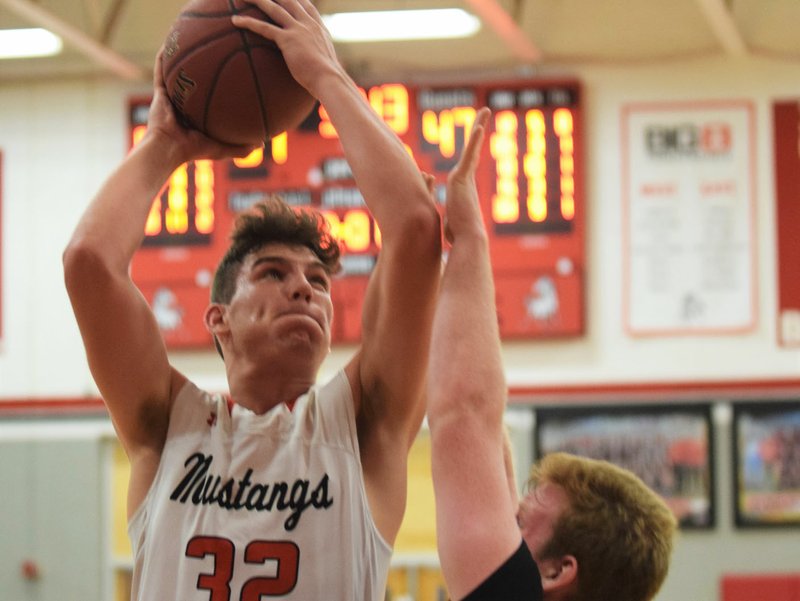 RICK PECK/SPECIAL TO MCDONALD COUNTY PRESS McDonald County's Cade Smith scores two of his game-high 25 points over Aurora's Trey Mulholland in the Mustangs' 92-85 in their season opener on Dec. 3 at MCHS.