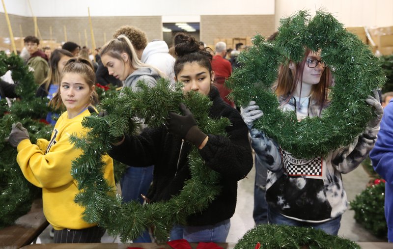 Natalie Inness (from left), 17, Ashley Davis, 17, and Kadee Daws, 17, all from Roland High School, fluff the branches of wreathes Wednesday during the Christmas Honors Wreath Workshop at the Fort Smith Convention Center. More than 16,000 wreaths were prepared for the Saturday morning Christmas Honors event Laying of the Wreaths at the Fort Smith National Cemetery. The event includes family time until 11 a.m., a ceremony at 11 a.m. and the public laying of the wreaths on headstones at 11:30 a.m.. Visit nwadg.com/photos to see more photos. NWA Democrat-Gazette/DAVID GOTTSCHALK