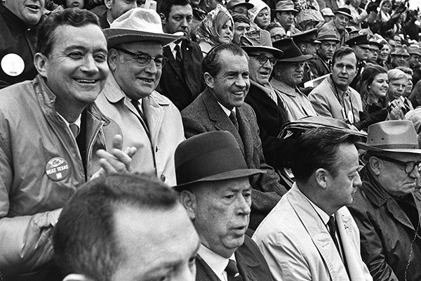 President Richard M. Nixon, second row, second from left, watches "The Big Shootout" football game between Arkansas and Texas in the stands at Razorback Stadium in Fayetteville, Ark., in this December 6, 1969 file photo. Seated beside Nixon from left are Rep. John Paul Hammerschmidt, R-Ark., Ark. Gov. Winthrop Rockefeller, Sen. John L. McClellan, D-Ark., Sen. J. William Fulbright, D-Ark., Rep. George H. Bush, R-Tex., and on the first row, left, University of Arkansas President David W. Mullins. Then ranked No. 1 Texas won the game and the national championship by defeating No. 2 Arkansas 15-14. (AP Photo/White House via Special Collections, University of Arkansas Libraries, Fayetteville, File)