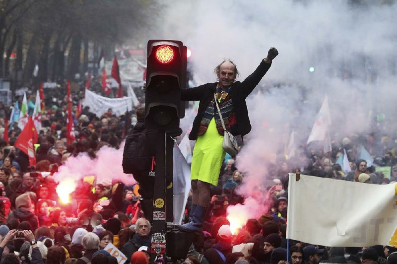 A protester stands on a traffic light Thursday as thousands of people on strike fill the streets in Paris. More photos are available at arkansasonline.com/126protest/ 