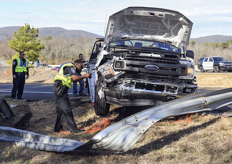 Hot Springs Police Officer Tyree Sampson takes photographs of a disabled pickup truck after the driver reportedly had a medical episode and wrecked into a guardrail near the eastbound lanes of the King Expressway at around 1:30 p.m. Thursday. - Photo by Grace Brown of The Sentinel-Record