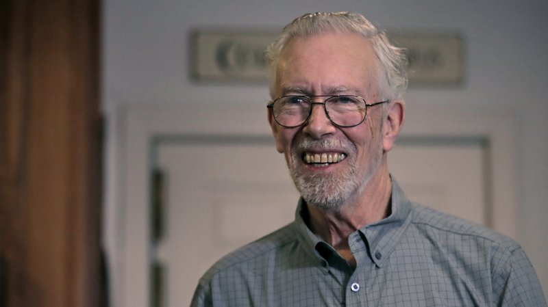 In this Nov. 22, 2019, photo, Charles Flagg, who is stricken with Alzheimer's disease, smiles as he makes a peanut butter sandwich for lunch at his family home in Jamestown, R.I. Flagg is participating in a study on the drug Aducanumab. New results were released on the experimental medicine whose maker claims it can slow the decline of Alzheimer's disease, the most common form of dementia. (AP Photo/Charles Krupa)