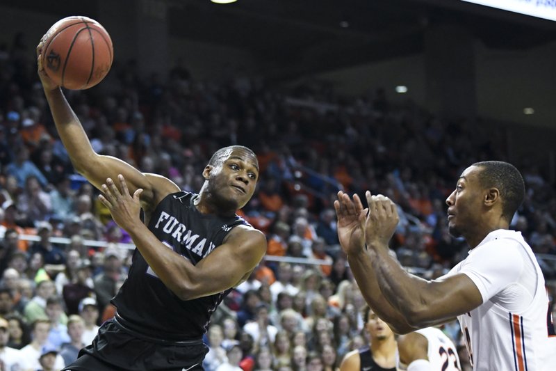 Furman guard Jordan Lyons (23) passes the ball over Auburn forward Anfernee McLemore (24) during the first half of Thursday's game in Auburn, Ala. - Photo by Julie Bennett of The Associated Press