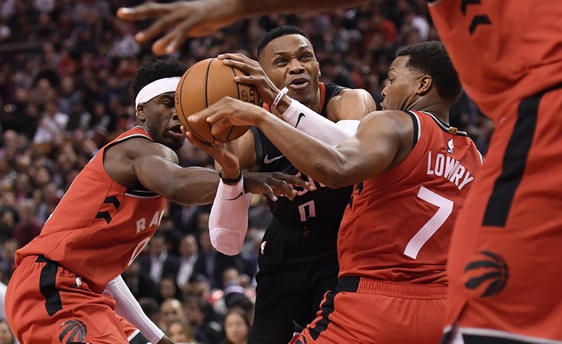 Houston Rockets guard Russell Westbrook (0) is fouled as he moves between Toronto Raptors guards Terence Davis, left, and Kyle Lowry (7) during the second half of Thursday's game in Toronto. - Photo by Nathan Denette of The Canadian Press via The Associated Press