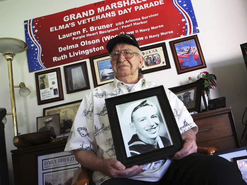 Lauren Bruner, one of the survivors of the Dec. 7, 1941, Japanese attack on the USS Arizona in Pearl Harbor, poses with a photo of himself at his home in La Mirada, Calif., in 2016. 