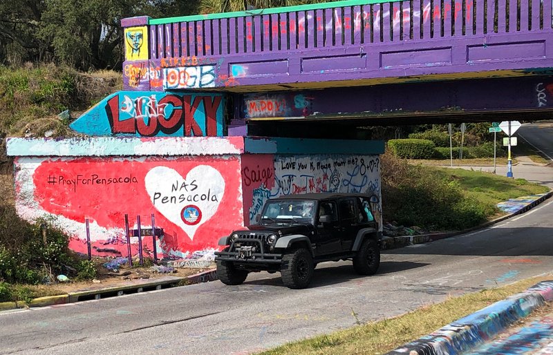 A vehicle drives by a tribute to victims of the Naval Air Station Pensacola that was freshly painted on what&#x2019;s known as Graffiti Bridge in downtown Pensacola, Fla., on Saturday, Dec. 7, 2019. A US official says the Saudi student who fatally shot three people at the Florida naval base had hosted a dinner party earlier in the week to watch videos of mass shootings. The official spoke on condition of anonymity after being briefed by federal investigators.&#xa0;The official says a second Saudi student was recording outside the building at the Naval Air Station Pensacola on Friday while the shooting was happening inside. The official also says 10 Saudi students are being held at the base and that several others are unaccounted for.&#xa0;&#xa0; (AP Photo/Brendan Farrington)