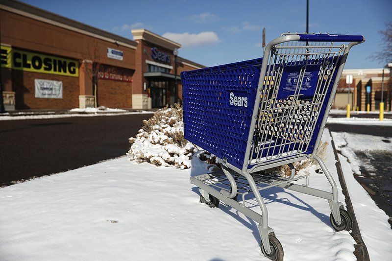 An empty shopping cart sits outside a Sears store earlier this year in the Streets of Southglenn mall in Littleton, Colo. 