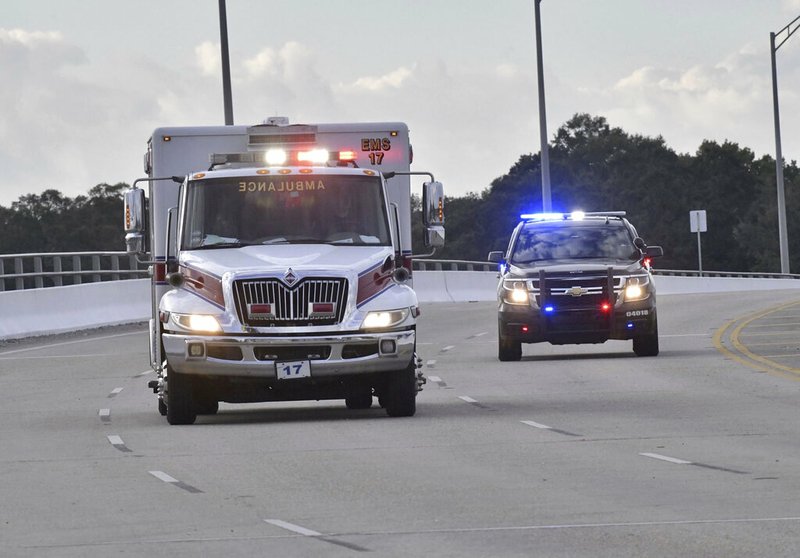 Police cars escort an ambulance after a shooter open fire inside the Pensacola Air Base, Friday, Dec. 6, 2019 in Pensacola, Fla. 