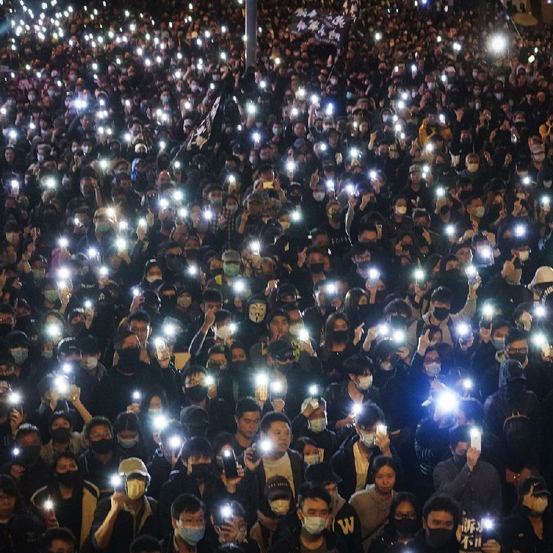 Pro-democracy protesters flash their smartphone lights Sunday as they gather on a street in Hong Kong. A march drawing hundreds of thousands of participants snaked through the streets, marking the start of the seventh month of the protest movement. There was limited violence surrounding the march. More photos are available at arkansasonline.com/129hongkong/. 