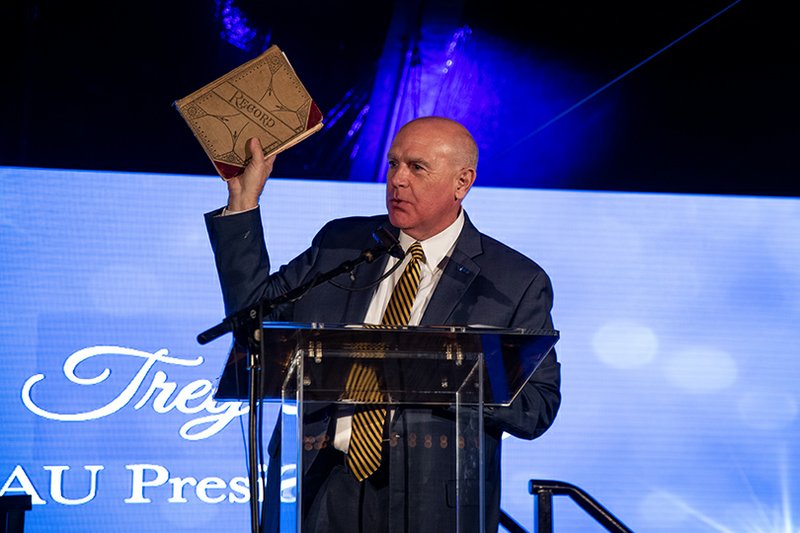 Dr. Trey Berry, president of SAU, holds aloft the minutes of the first meeting of the Board of Trustees dating back to 1909 during the Lights Love and Loyalty celebration on the campus of Southern Arkansas University Saturday, Dec. 7, 2019.