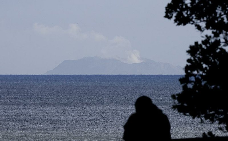 A man in Whakatane, New Zealand, watches today as a plume of steam and ash rises from the volcano on White Island. More photos are available at arkansasonline.com/1210newzealand/ 