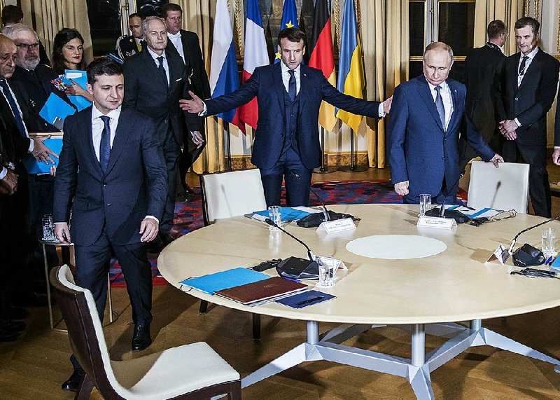 French President Emmanuel Macron (center) ushers Ukrainian President Volodymyr Zelenskiy (left) and Russian President Vladimir Putin to their seats Monday at the Elysee Palace in Paris during a summit where leaders sought to find a way to end the fighting in eastern Ukraine. More photos are available at arkansasonline.com/1210paris/. 