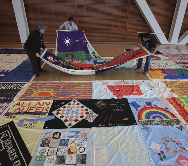 Pam Jones (left) of Benton, Brad Gammell (middle), with the AIDS Memorial Quilt's The Names Project Foundation, and volunteer Christian Barenes lay out a section of the AIDS Memorial Quilt at the Clinton Presidential Center in observance of World AIDS Day in this 2014 photo. The quilt contains panels for two of Jones' sons, J.D. Thomas and Kevin G. Thomas. The quilt is headed home to San Francisco to become part of the National AIDS Memorial. (Photo by Staton Breidenthal, Arkansas Democrat-Gazette)