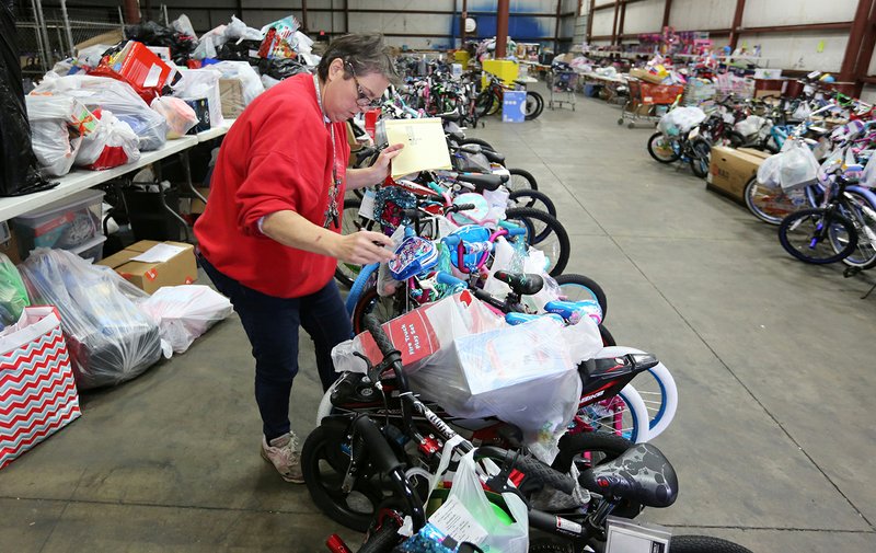 Major Michelle Robbins, with The Salvation Army of Northwest Arkansas, helps organize donated items Monday for the annual Salvation Army Angel Tree program inside the distribution center in Springdale. The program will provide for more than 700 families and 2,000 children. The Salvation Army is still in need of items for children ages 10-12. The collection boxes will be out through Wednesday. Distribution of the donated items is December 19 and 20. NWA Democrat-Gazette/DAVID GOTTSCHALK