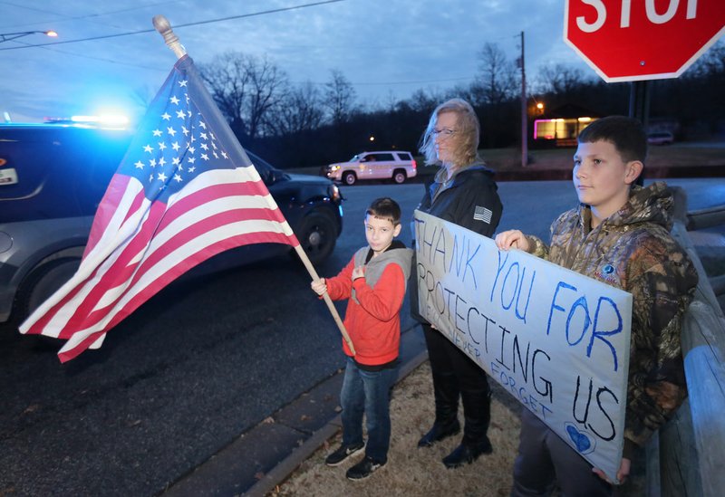 NWA Democrat-Gazette/DAVID GOTTSCHALK James O&#xe2;&#x20ac;&#x2122;Connor (right), 12, stands with his brother Jordan, 9, and Kelly Cantrell, with the Washington County Sheriff's office Monday, December 9, 2019, as the processional carrying slain Fayetteville police officer Stephen Carr from the Washington County Coroner's office to Little Rock passes by. Carr, 27, was shot and killed about 9:40 p.m. Saturday while in his patrol vehicle in the parking lot behind the police station.