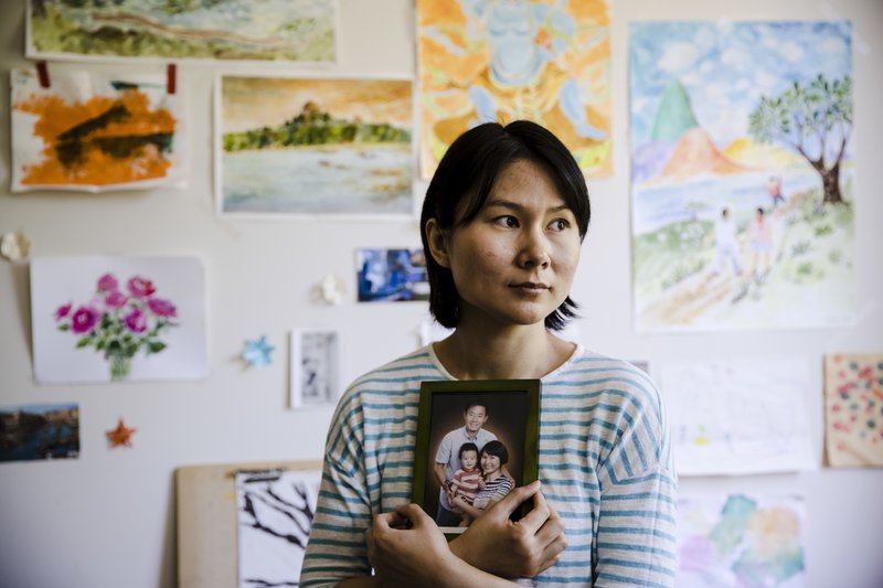 FILE - In this Wednesday, May 9, 2018 file photo, Hua Qu, the wife of detained Chinese-American Xiyue Wang, poses for a photograph with a portrait of her family in Princeton, N.J. Iran's foreign minister says a detained Princeton graduate student will be exchanged for an Iranian scientist held by the U.S. Mohammed Javad Zarif made the announcement on Twitter on Saturday, Dec. 7, 2019. The trade involves graduate student Xiyue Wang and scientist Massoud Soleimani. Wang was sentenced to 10 years in prison in Iran for allegedly &#x201c;infiltrating&#x201d; the country and sending confidential material abroad. His family and Princeton strongly denied the claims. (AP Photo/Matt Rourke, File)