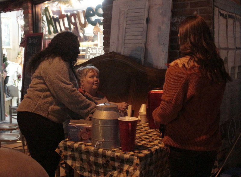 Mary Taylor, right, is served hot chocolate by Katrina Embry, Smackover Chamber of Commerce Vice President, and Lisa Lindsey, owner of the Hen’s Nest, during Smackover’s Christmas on Broadway celebration in 2019. This year's holiday celebration will look a little different due to the COVID-19 pandemic; city residents will be able to see the lighting of the Christmas tree, hear a reading of "Eddie's Cross" about Smackover man Eddie Rouse and have a socially-distance visit with Santa. (News-Times file)