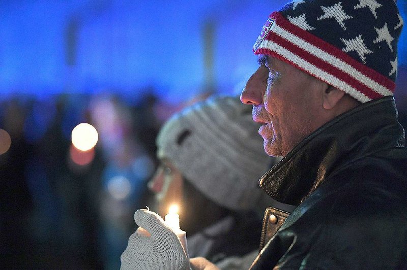 Samuel Tejada of Springdale holds a candle Tuesday during a vigil in Fayetteville for police officer Stephen Carr, who was shot and killed while sitting in his patrol vehicle late Saturday. Officers who heard the gunshots briefly chased the suspected shooter, London Phillips, into an alley, shooting and killing him. More photos are available at arkansasonline.com/1211vigil/
(NWA Democrat-Gazette/J.T. Wampler)