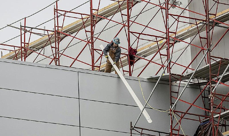 Workmen move materials around on a scaffolding that wraps around a portion of the Simmons Bank Arena facade in North Little Rock Tuesday December 10, 2019.  (Arkansas Democrat-Gazette/ John Sykes Jr.)