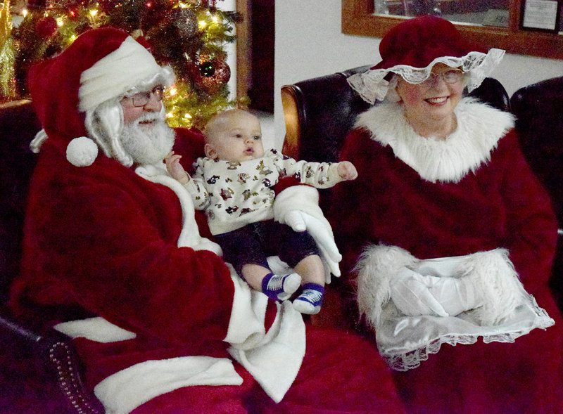 Westside Eagle Observer/MIKE ECKELS Santa and Mrs. Claus pose with Carter Cain for a photograph during the post parade festivities at Grand Saving Bank in Decatur Dec. 6. Santa and his wife brought up the rear of the Decatur Christmas Parade which made its way down Main Street.