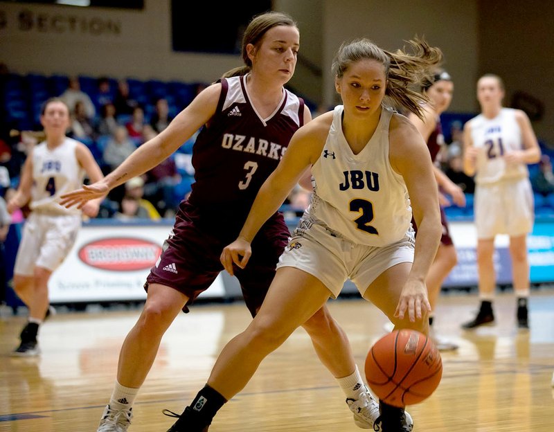 Photo courtesy of JBU Sports Information John Brown senior Sarah Williams dribbles the ball as College of the Ozarks' Abby Oliver defends during last Saturday's game inside Bill George Arena.