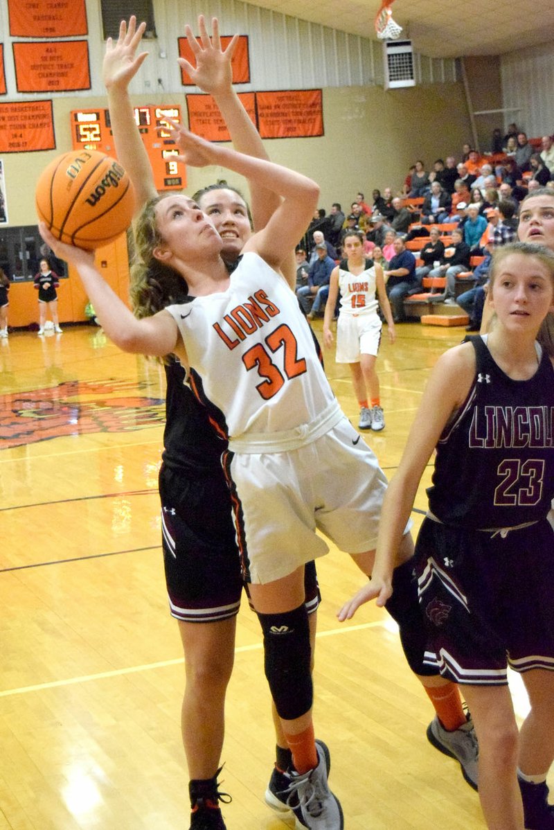 Westside Eagle Observer/MIKE ECKELS Kaylan Chilton (Lions 32) fights off a Lady Wolves player to put up a jumper during the third quarter of the Gravette-Lincoln varsity girls basketball contest in Gravette Dec. 3. Gravette won 63-33.