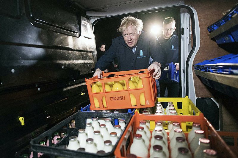 British Prime Minister Boris Johnson loads a crate of juice into a delivery van before dawn Wednesday in northern England as he and other political leaders campaigned on the eve of today’s national election that will determine Britain’s path to Brexit. Polls have shown Johnson’s party in the lead, but surveys suggest the margin is tightening. More photos are available at arkansasonline.com/1212election/. Video is available at arkansasonline.com/1212johnson/.
(AP/Stefan Rousseau)