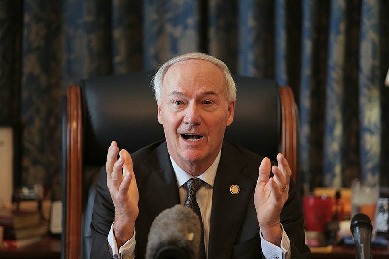 Governor Asa Hutchinson takes questions from reporters at his office in the state capitol in Little Rock.