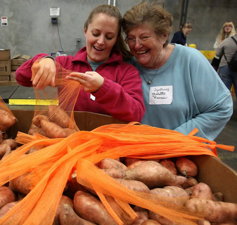 Arkansas Democrat-Gazette/THOMAS METTHE Whitney Bohn (left) of Springdale laughs with her grandmother, Charlotte Harrison of Alexander, as they bag sweet potatoes during the Ingathering 2019 at the Arkansas Food Bank in Little Rock. About 400 volunteers from 70 churches across the state participated in the event.