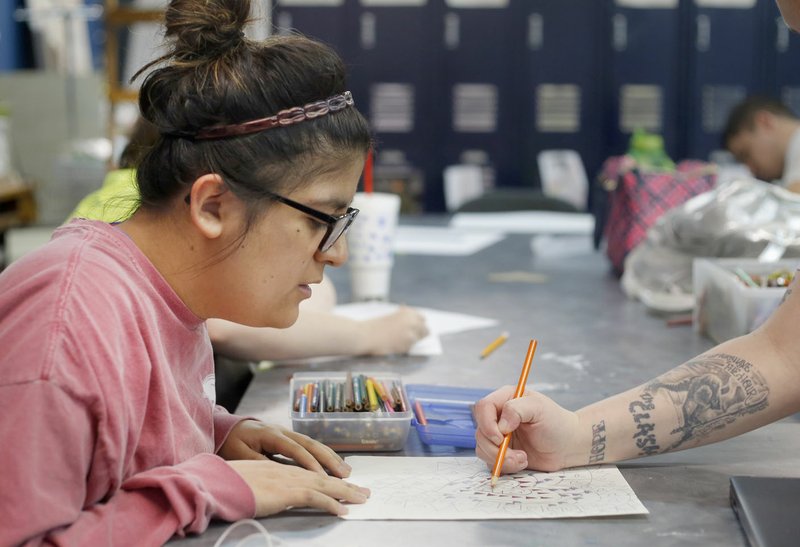 File Photo/DAVID GOTTSCHALK A client watches the hand of Brandi Tyner, lead art teacher at the Life Styles Blair Center in Springdale, as she works on a rough draft for a table centerpiece.