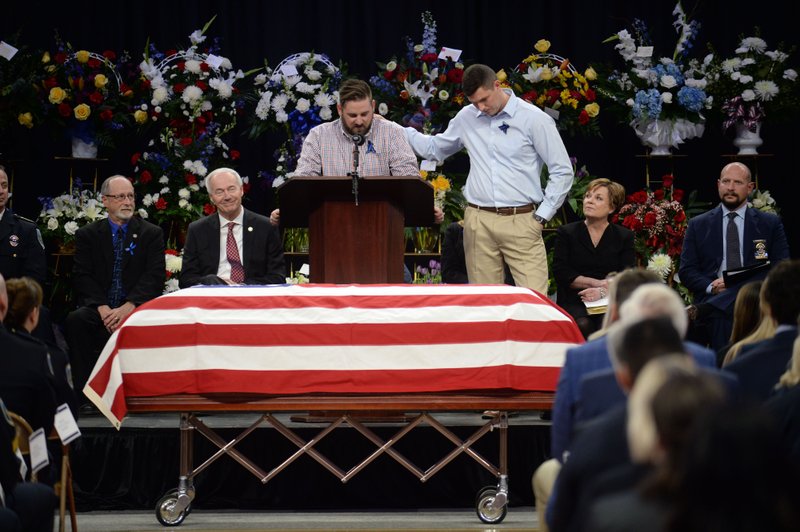 David Layman (center) and John Collier, both friends of officer Stephen Carr of the Fayetteville Police Department, tell stories of their friend and roommate Thursday during a public funeral service for Carr at Bud Walton Arena on the University of Arkansas campus in Fayetteville. Carr died Saturday. NWA Democrat-Gazette/ANDY SHUPE