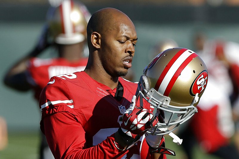 In this Jan. 15, 2014 file photo, San Francisco 49ers cornerback Carlos Rogers adjusts his helmet during practice at an NFL football training facility in Santa Clara, Calif. Ten former NFL players have been charged with defrauding the league’s healthcare benefit program. They include five who played on the Washington Redskins, including Clinton Portis and Carlos Rogers. (AP Photo/Jeff Chiu)
