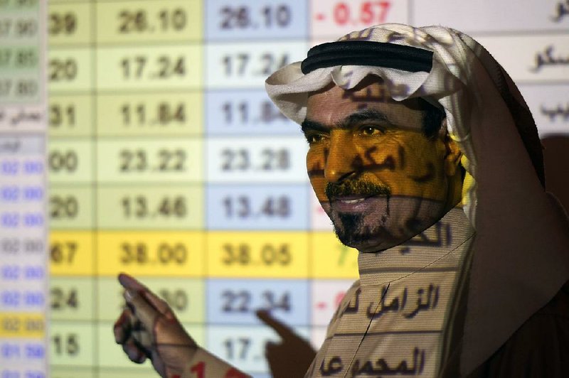 A stock trader stands in front of a screen displaying the Saudi stock market Thursday in Riyadh, Saudi Arabia. Shares in Saudi Aramco rose on the second day of trading. More photos are avail- able at arkansasonline.com/1213aramco/  
