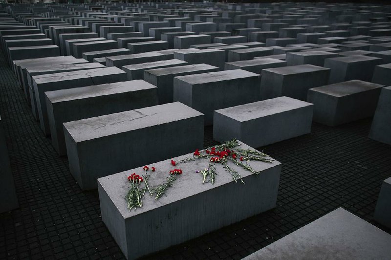 Flowers lie on a concrete slab of the Holocaust Memorial in Berlin. One of Germany’s richest families has started a foundation to support Holocaust survivors and promote Holocaust education to atone for the family company’s use of Nazi slave labor during World War II.  